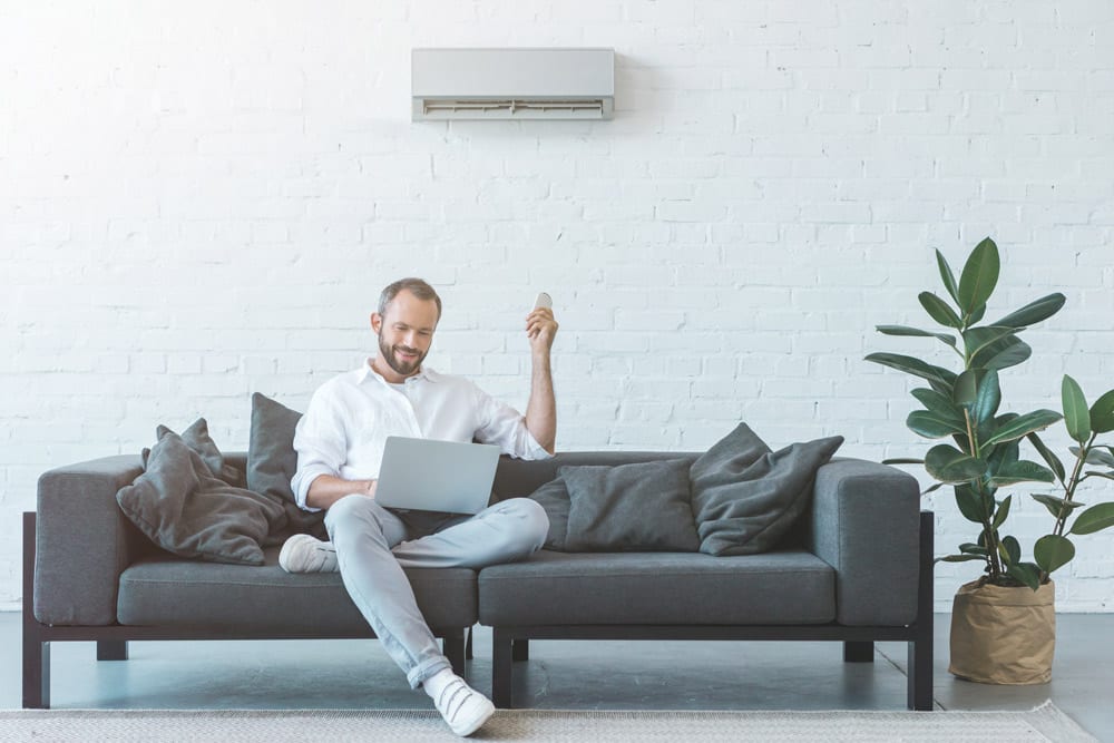 Man controls ductless AC system using remote control