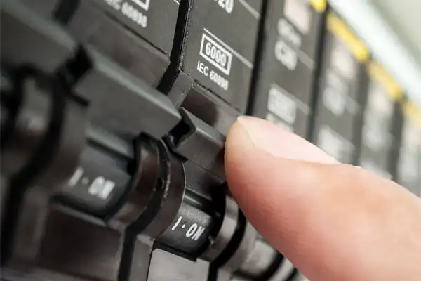 A close-up of a person's finger flipping a switch on an electrical circuit breaker panel during a Circuit Breaker Installation in Boston, MA.